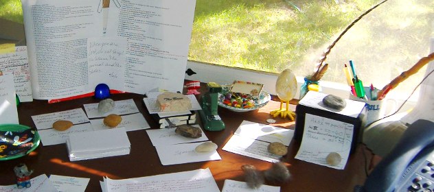 Lisa Dale Norton's writing desk at her cabin in the Sandhills. Norton is a developmental editor offering comprehensive manuscript editing. Her desk is covered with manuscript papers and notecards, mementoes and a collection of quartz rocks collected on rambles which she uses to anchor her papers.